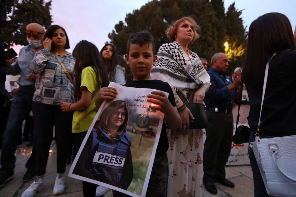 Palestinians carry candles and pictures of slain Al Jazeera journalist Shireen Abu Akleh, to condemn her killing at the Manger Square of the Church of the Nativity in the West Bank city of Bethlehem on May 16, 2022. (Photo: Ahmad Tayem/APA Images)