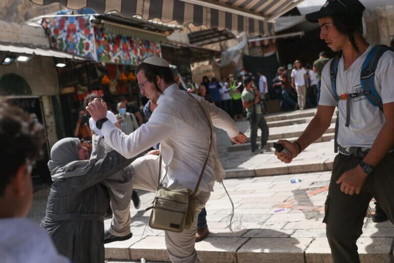 Israeli settler attacks Palestinian woman in Jerusalem's Old City during the 'Jerusalem Day' flag march, May 29, 2022. The flag march is an annual display of right-wing Israeli nationalism and anti-Palestinian racism intended to celebrate Zionist forces’ seizure of East Jerusalem in 1967. (Photo: Ohad Zweigenberg/social media)