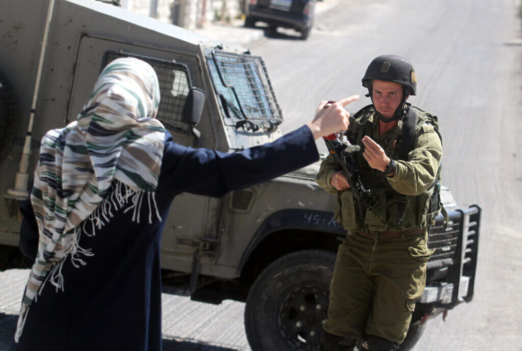 A Palestinian woman encounters an Israeli soldier blocking the road during an army operation in the West Bank city of Ramallah, Monday, Oct. 7, 2013. (Photo: Issam Rimawi/APA Images)