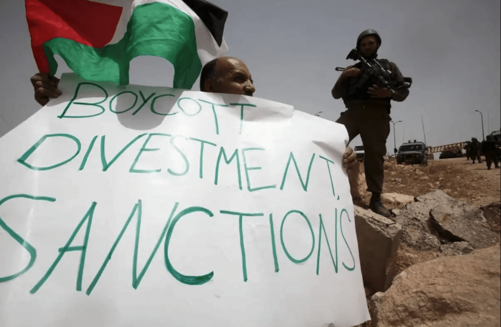 A Palestinian holds a placard reading "Boycott Divestment, Sanctions" as part of a protest on June 8, 2013 near the Jewish settlement of Bat Ayin and the West Bank village of Surif, west of Hebron. (Photo: Hazem Bader/AFP via Getty Images)
