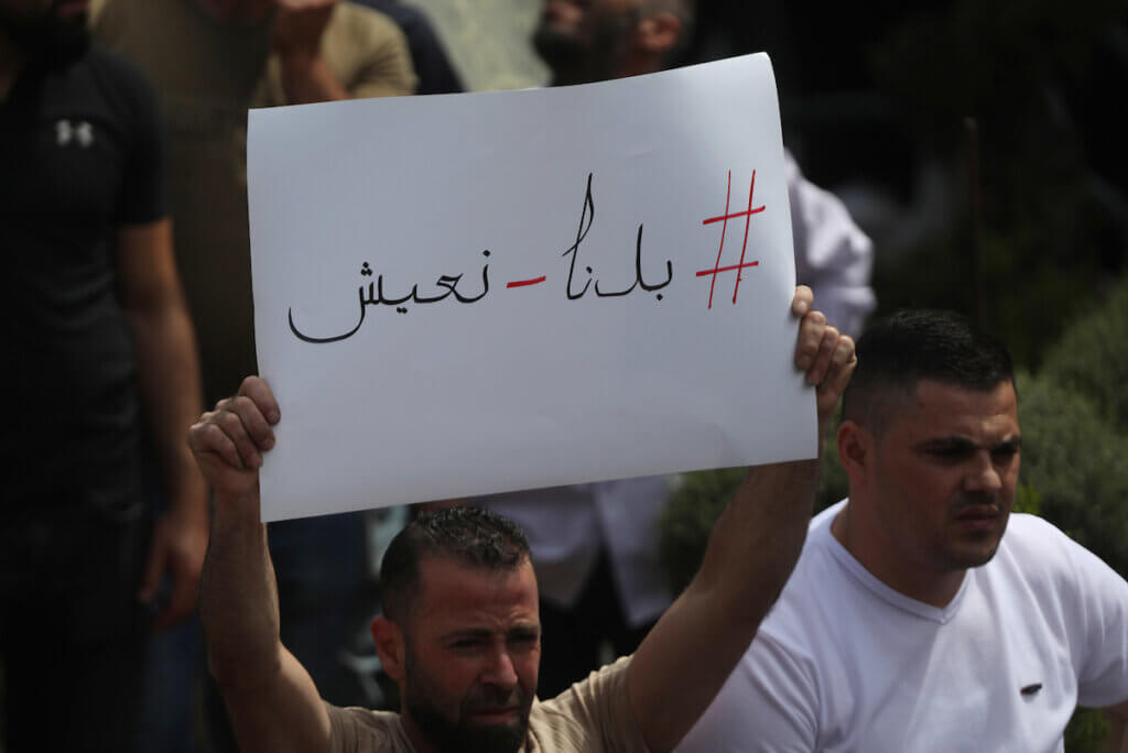 A Palestinian protester holds up a sign that says, "We want to live" during protests against the rising prices of essential goods in the West Bank city of Hebron, on June 5, 2022. (Photo: Mamoun Wazwaz/APA Images)