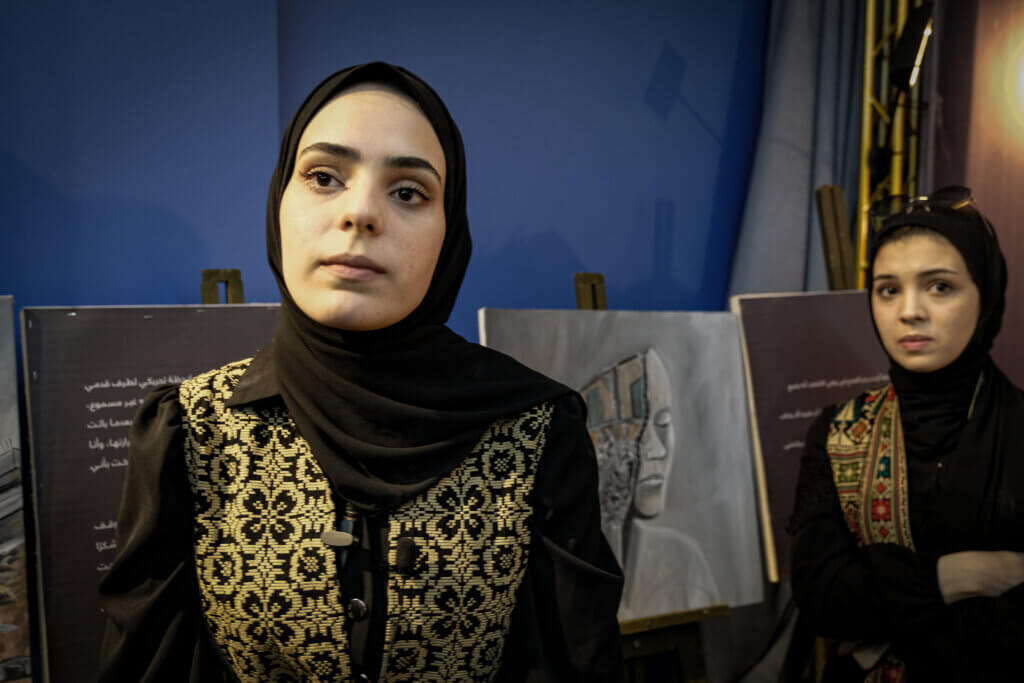 Zainab al-Qolaq, left, at the exhibition of her paintings titled, “I’m 22 years old, I lost 22 people” (Photo: Mohamed Salem)