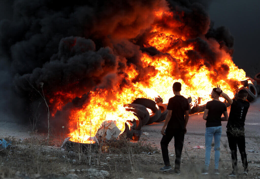 Youths burn tires during a protest against the killing of 4 Palestinians by Israeli forces near Hawara military checkpoint, in the West Bank city of Nablus on September 28, 2022. (Photo: Stringer/APA Images)