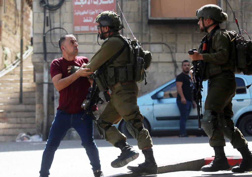 Israeli forces detain a Palestinian man during clashes following a protest against the killing of 4 Palestinians in an Israeli military raid into the Jenin refugee camp in the West Bank city of Hebron on September 29, 2022. (Photo: Mamoun Wazwaz/APA Images)