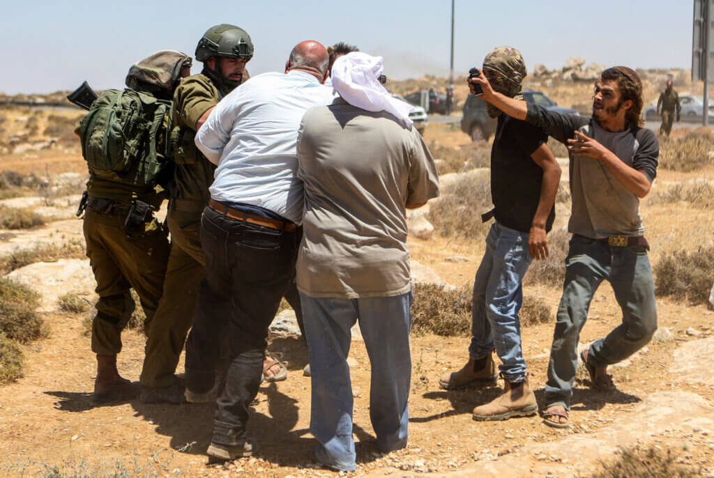A Jewish settler pepper sprays the face of a Palestinian protester.