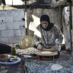 A Palestinian woman rolls out dough for baking.