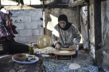 A Palestinian woman rolls out dough for baking.