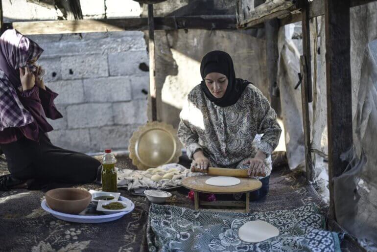 A Palestinian woman rolls out dough for baking.