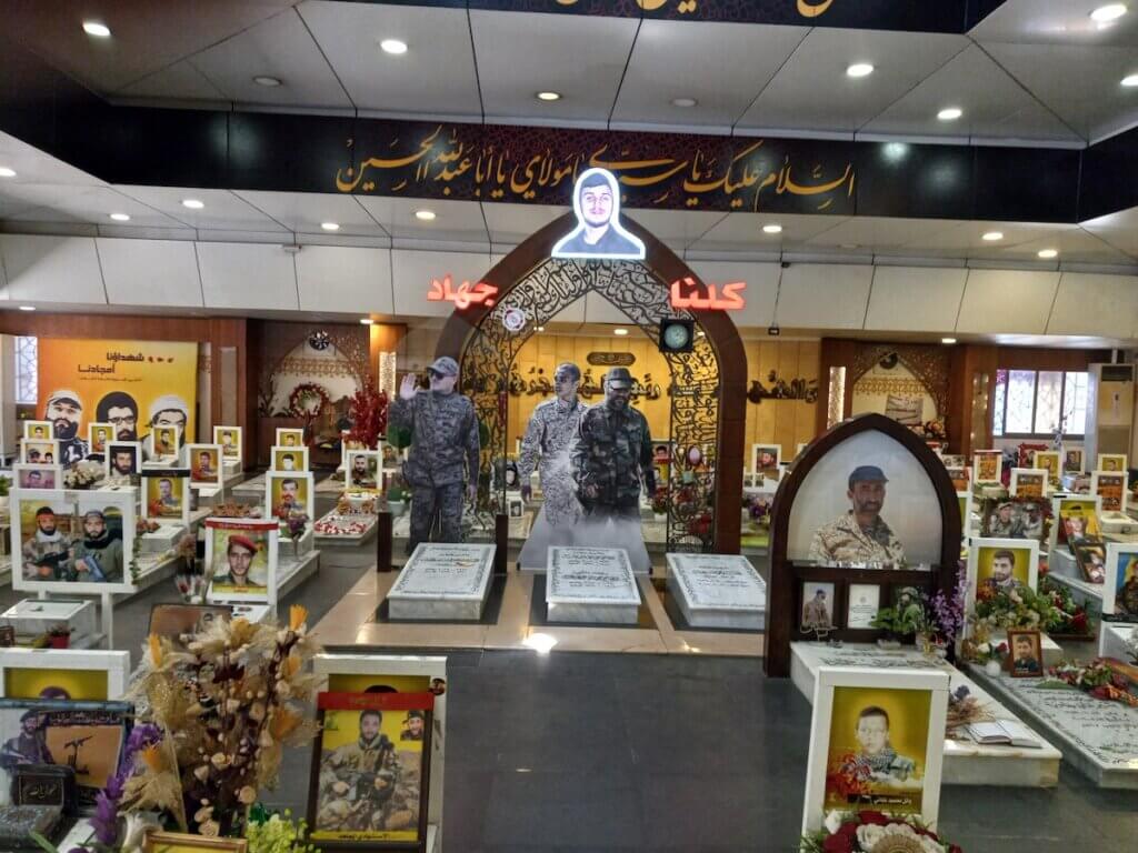 Hezbollah Martyr cemetery in Beirut; in the center, Imad Mughniyah, a picture containing text, indoor, ceiling, shop on the right, his son in the center, and the slogan "All of Us for Jihad" (Photo: Jeff Klein)