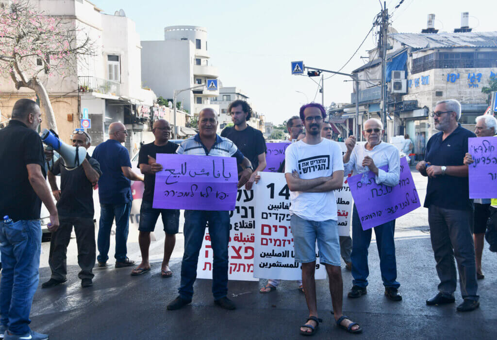 An activist holds a sign that says, "Jaffa is not for sale," as protesters obstruct traffic during a demonstration against the displacement of Palestinians in Jaffa. (Photo: Jessica Buxbaum)