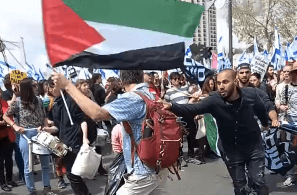Screenshot of video showing protesters and security forces wrestling a Palestinian flag out of another protester's hands during an anti-Netanyahu protest in Israel. (Image: Twitter/@FadiAmun)