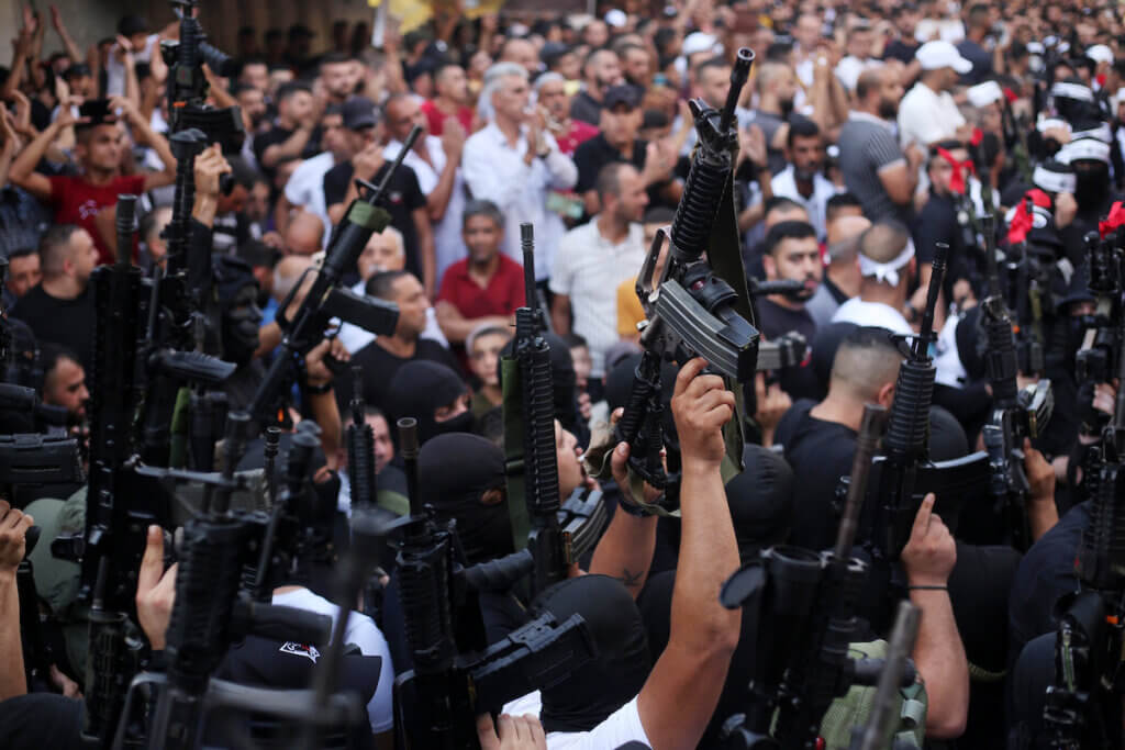 Members of the Palestinian resistance hold their weapons during a memorial service for Mohammed al-Azizi and Abdul Rahman Sobh, who were killed by Israeli forces in July 2022, in the West Bank city of Nablus. (Photo: Shadi Jarar'ah/APA Images)