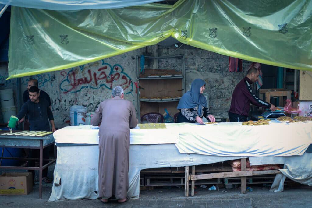 Mariam Salha works at a qatayef stand with her sons in Gaza. (photo: Mohammed Salem, Mondoweiss)