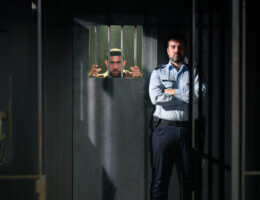 A still from Prisoners of the Occupation in Denmark, with Arian Kashef (l) and Martin Hylander (r). The scene shows an Israeli prison guard standing in front a cell with a Palestinian prison looks out from behind bars. (Photo by Søren Meisner of Teater Gaius)