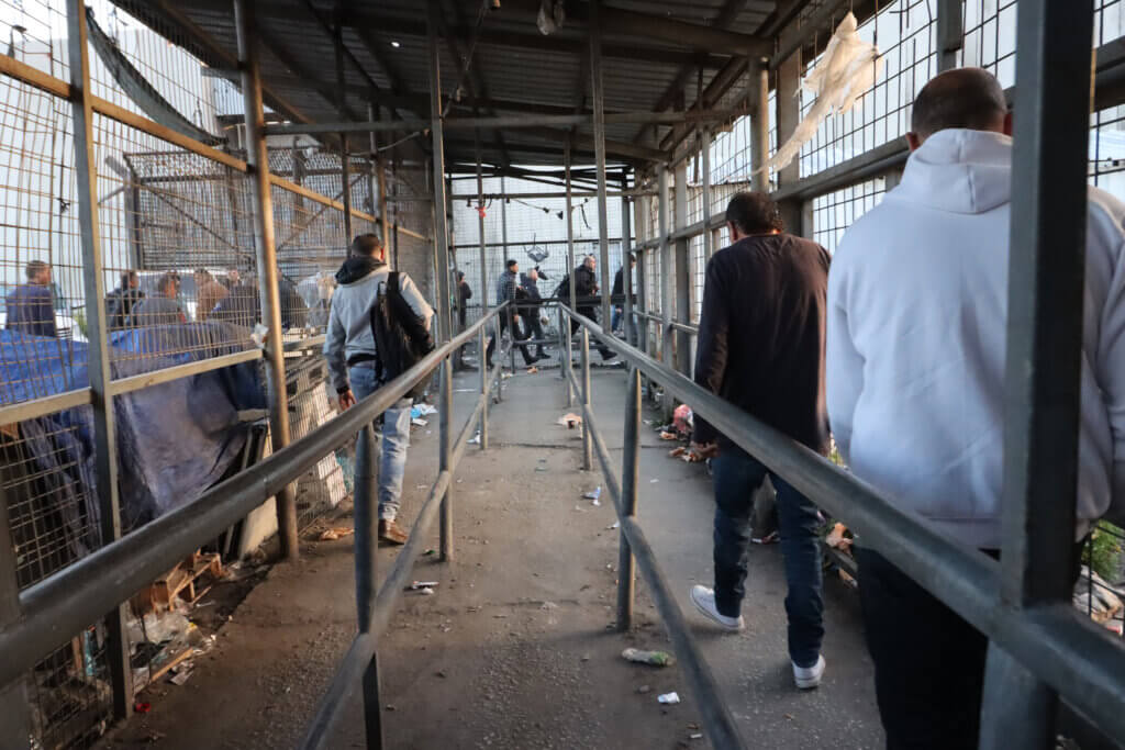 Thousands of Palestinian workers cross the Israeli Eyal checkpoint in Qalqilya, West Bank, on their daily trip to workplaces in Israeli settlements and Palestinian towns behind the Israeli colonial wall, in March 2023. (Photo: Ahmad Al-Bazz, Activestills)