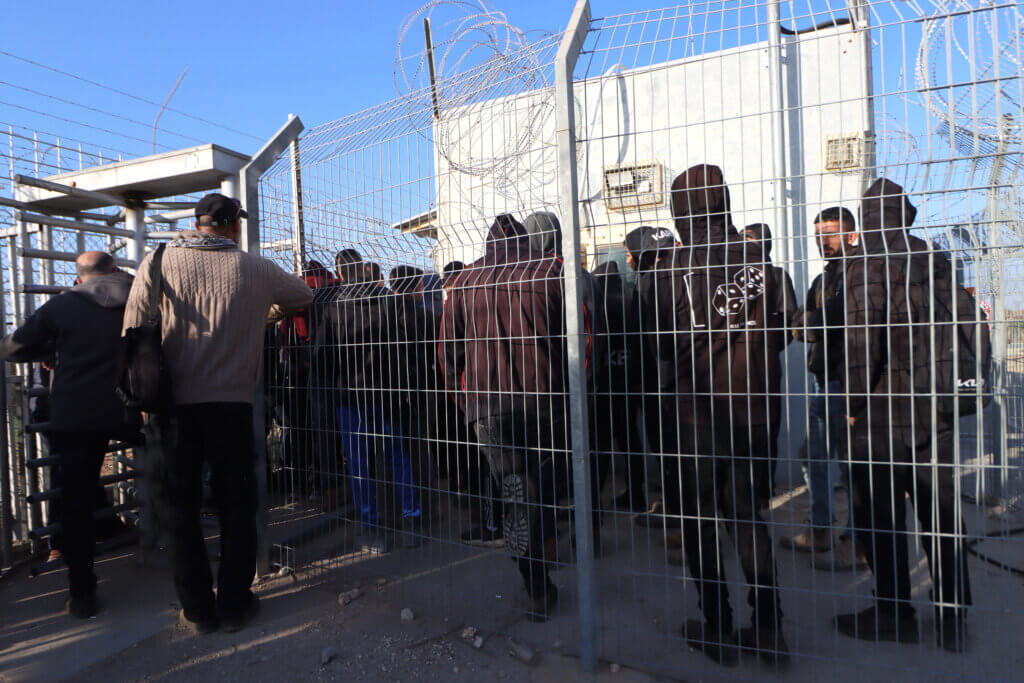 Palestinian farmers line up at an Israeli military gate in West Bank village of Hablah to reach their agricultural land located behind the Israeli colonial wall, in March 2023. (Photo: Ahmad Al-Bazz, Activestills)