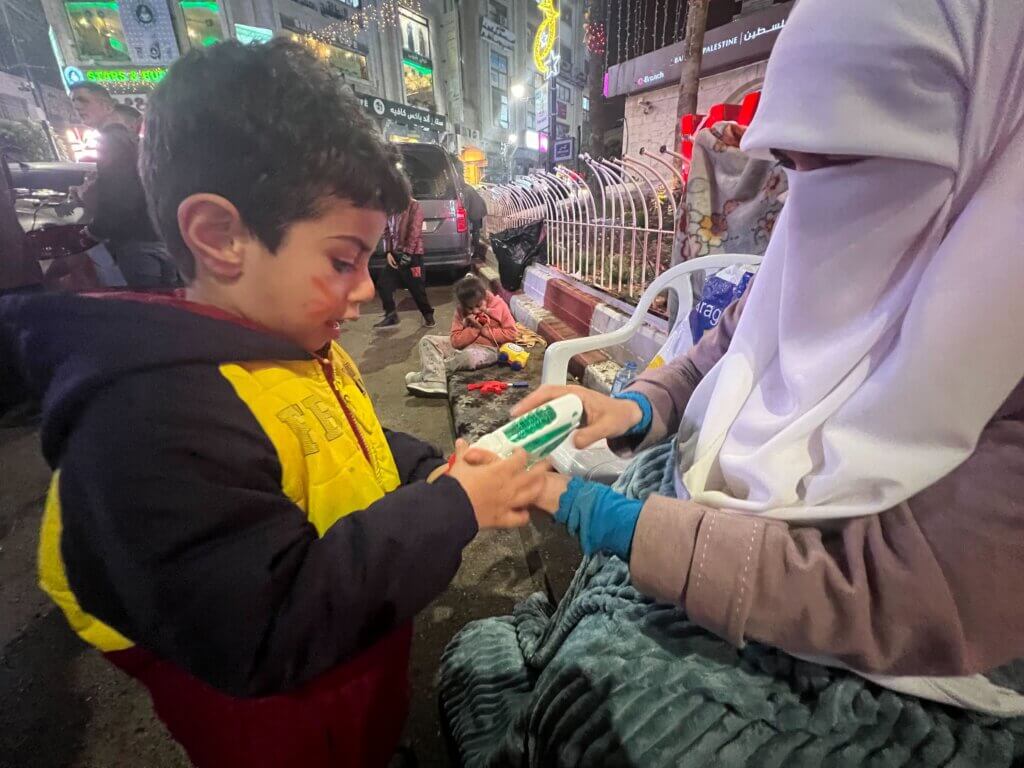 Randa Moussa, wife of Khader Adnan, with her son Omar, playing with his water gun, at al-Manara Square in Ramallah at a sit-in for her husband.
