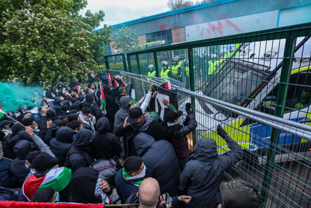 A crowd of activists chant slogans and hold Palestinian flags outside an Elbit UAV weapons factory in Leicester, England to support “Palestine Action” activists who occupied the building for six consecutive days in May 2021. (Photo by Vudi Xhymshiti)
