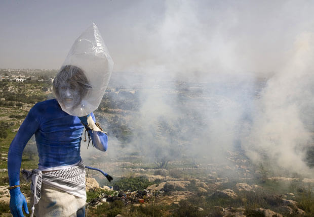 The Na'vi man covers his head with a plastic bag as tear gas is fired during the weekly demonstration against Israel's controversial separation barrier. (Photo: AFP/GETTY)