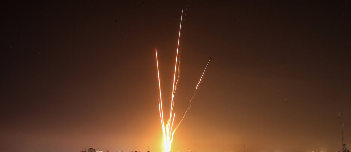 Night image of Palestinian rockets fired from Gaza towards Israel, with Gaza's urban sprawl in the foreground.
