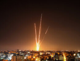 Night image of Palestinian rockets fired from Gaza towards Israel, with Gaza's urban sprawl in the foreground.