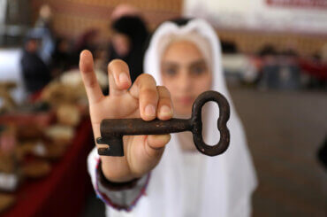 Photo showing a Palestinian girl holding up an old rusted key to a Palestinian home that was ethnically cleansed of its inhabitants in 1948.