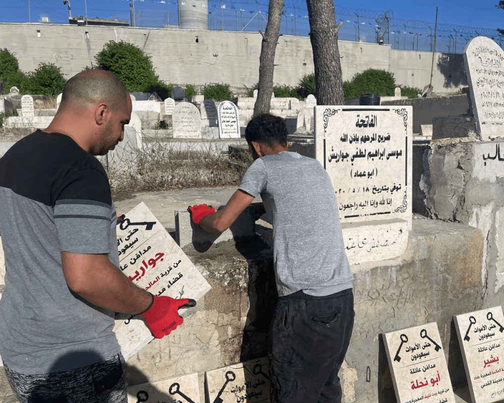 Palestinians place gravestones that read "even the dead will return" on the graves of Palestinian refugees in the Aida refugee camp. (Photo: PNN)