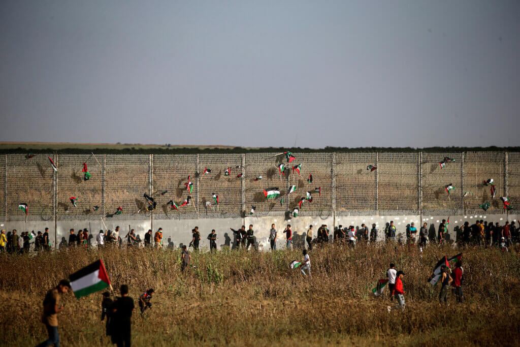 Palestinian protesters mount the Palestinian flag on the border fence between Israel and Gaza during a Palestinian "flag march" demonstration on the border with Israel, east of Gaza city, in response to the annual Israeli Flag March, May 18, 2023.