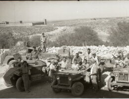 Historical photo from 1948 portraying the occupation of Iraq Suwaydan. Israeli soldiers are shown carrying rifles and riding their military jeeps as they pose for the camera, while in the background there is a stone fence and the plains of Iraq Suwaydan extending in the background, and the old British Police station can be seen in the distance.