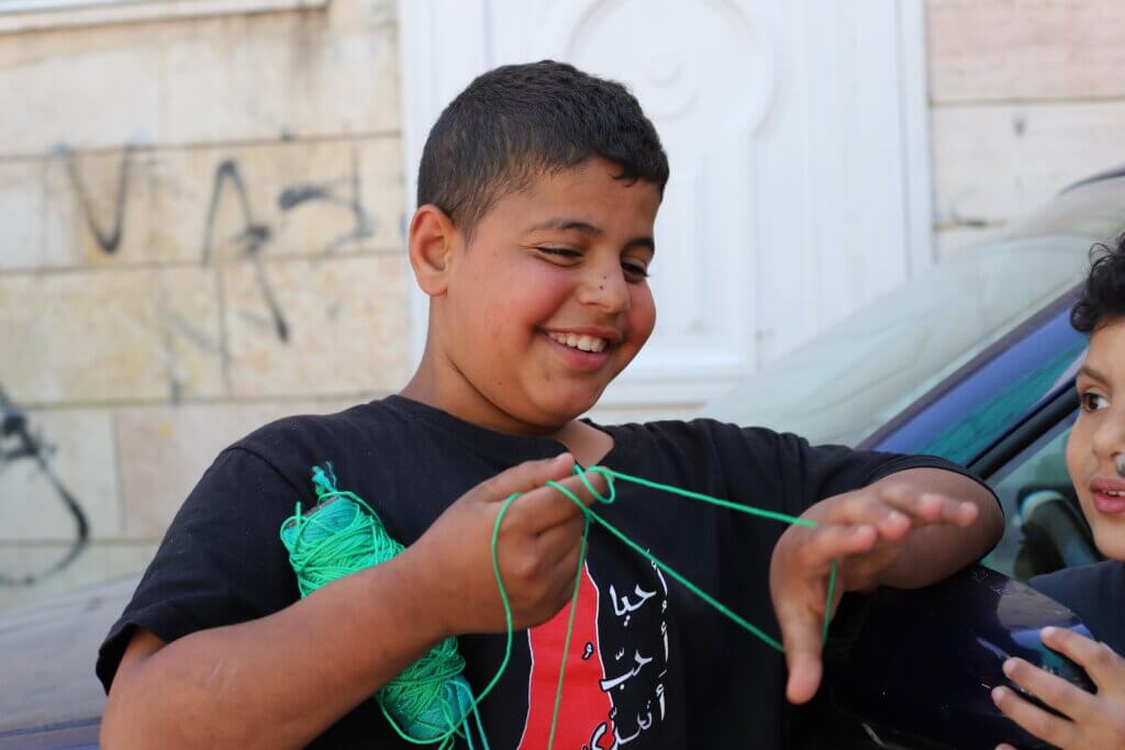 Ayham, 12 (left), and Mahmoud, 6, (right) untangle the line of a kite as they get ready to play in the streets of the camp. (Malik Hamamra/Mondoweiss) Aida refugee camp, occupied West Bank, May 2023.