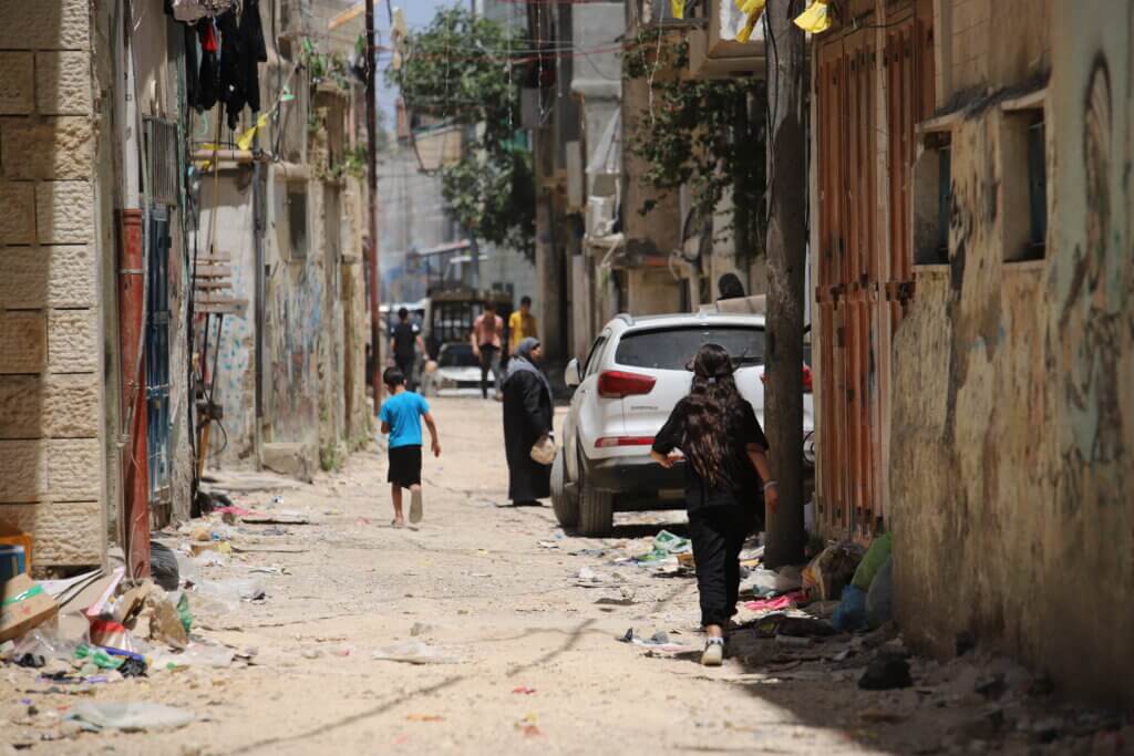 Palestinians walk down a street in one of the neighborhoods in the Aida refugee camp. (Malik Hamamra/Mondoweiss) Aida Refugee Camp, occupied West Bank, May 2023.