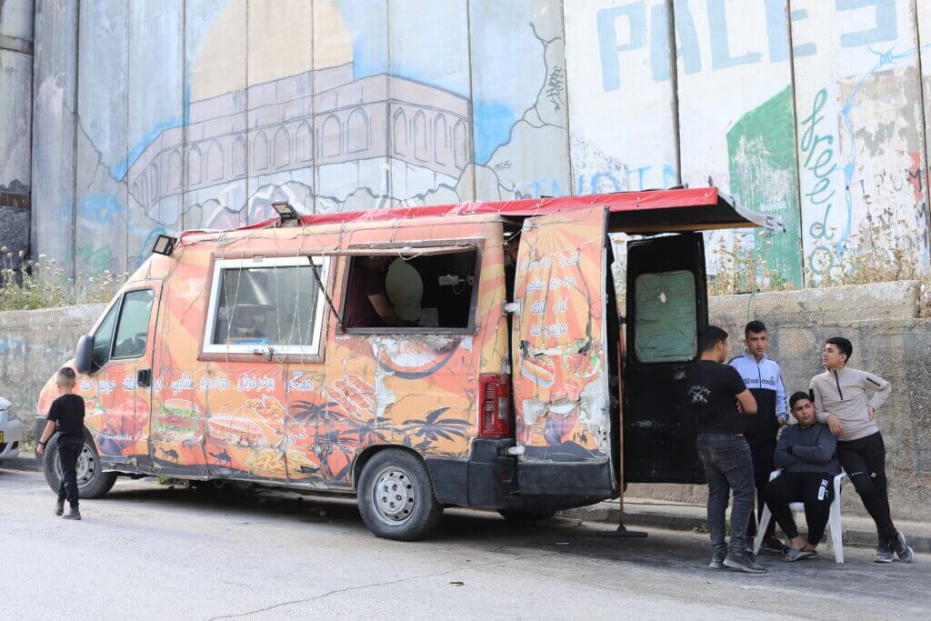 Muntassir's food truck parked in front of Israel's separation wall. (Malik Hamamra/Mondoweiss) Aida Refugee Camp, occupied West Bank, May 2023.
