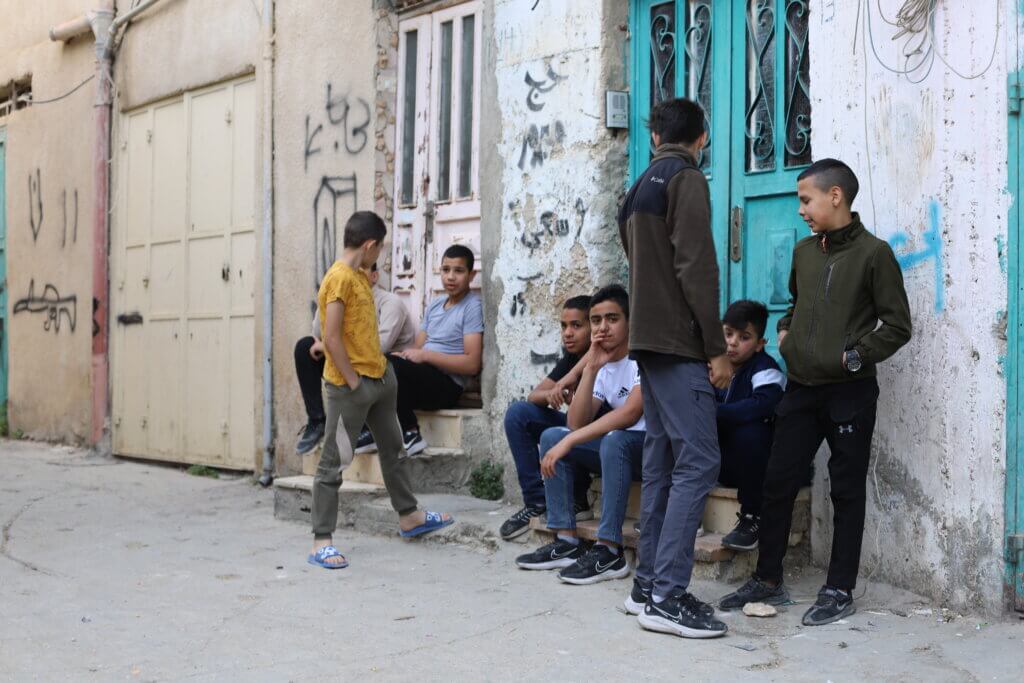 A group of boys hang out in the street in the Aida refugee camp. (Malik Hamamra/Mondoweiss) Aida Refugee Camp, occupied West Bank, May 2023.