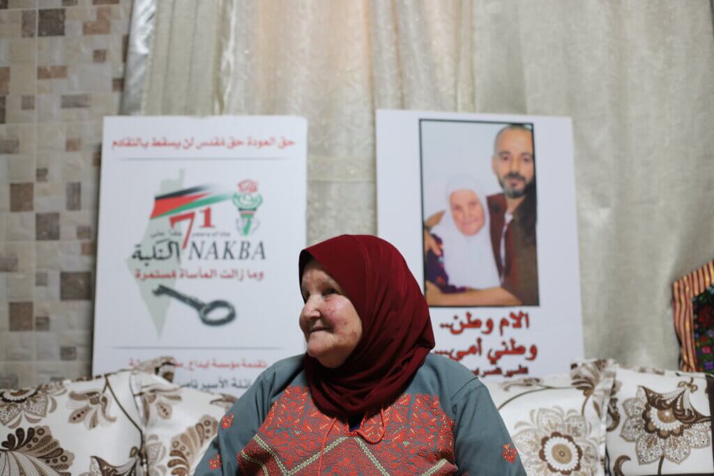 Mazyouna Abu Srour sits in front of a photo of her and her son, Nasser, taken inside an Israeli prison, where Nasser has been held for 32 years. 