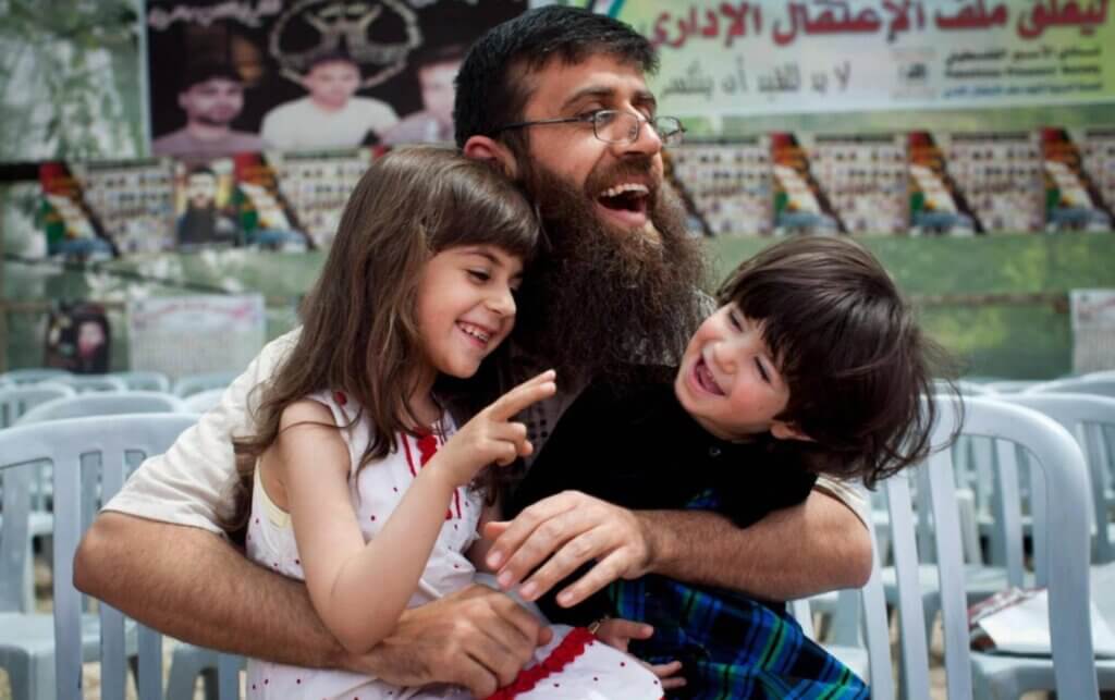Khader Adnan holding two of his daughters in his lap as all three of them laugh, during his reception in his hometown of Arrabeh near Jenin after being released from Israeli prison in April 2012.