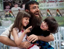 Khader Adnan holding two of his daughters in his lap as all three of them laugh, during his reception in his hometown of Arrabeh near Jenin after being released from Israeli prison in April 2012.