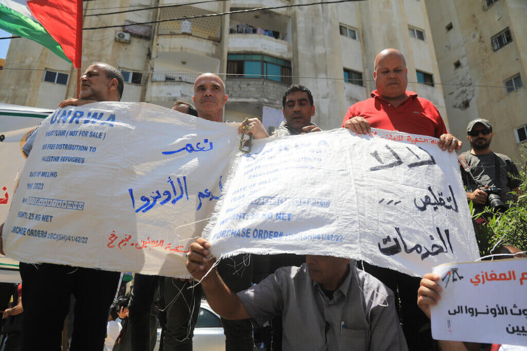 Palestinians hold food ration bags turned into protest signs during a rally outside the headquarters of the United Nations Relief and Works Agency (UNRWA), in Gaza City on June 20, 2023. (Photo: Youssef Abu Watfa/APA Images)