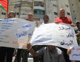 Palestinians hold food ration bags turned into protest signs during a rally outside the headquarters of the United Nations Relief and Works Agency (UNRWA), in Gaza City on June 20, 2023. (Photo: Youssef Abu Watfa/APA Images)