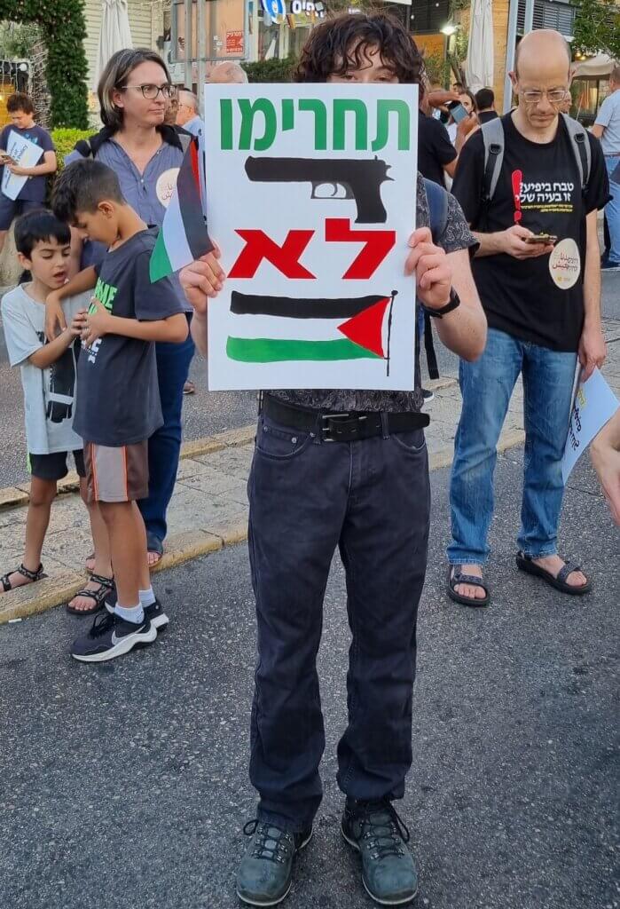 A protester holding a poster that says, "Confiscate [Guns], Not [Palestinian Flags]" at a demonstration organized by the High Follow-Up Committee in Haifa, June 24, 2023. (Photo: Yoav Haifawi)