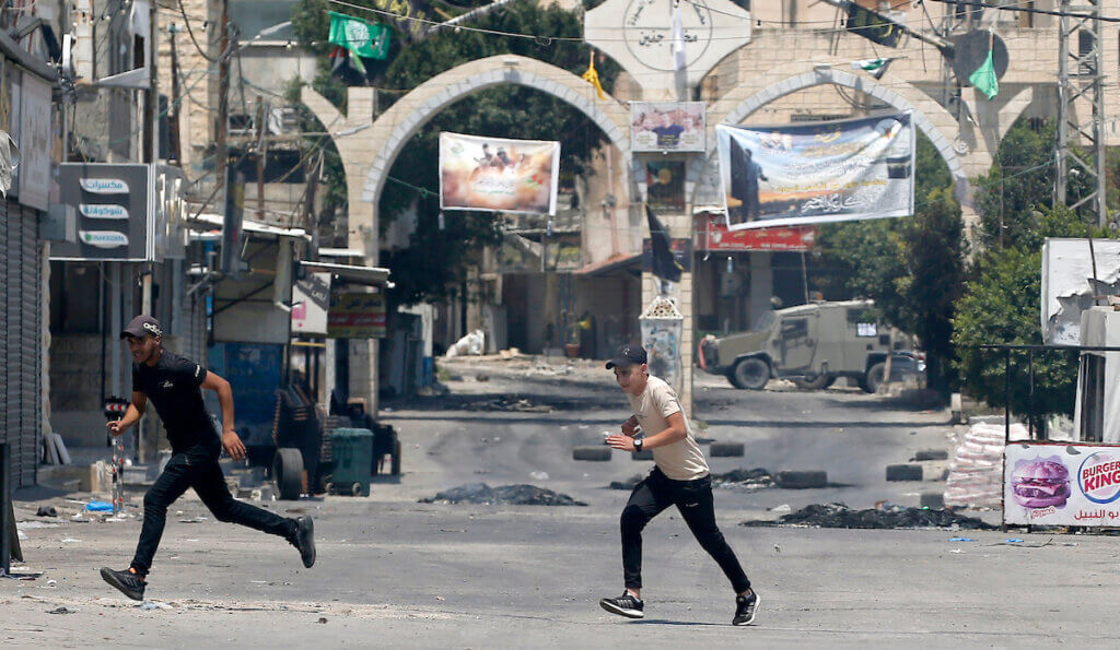 Palestinians run for cover amid clashes during an Israeli military operation in Jenin, West Bank, 03 July 2023. (Photo: © Alaa Badarneh/EFE via ZUMA Press/ APA Images)