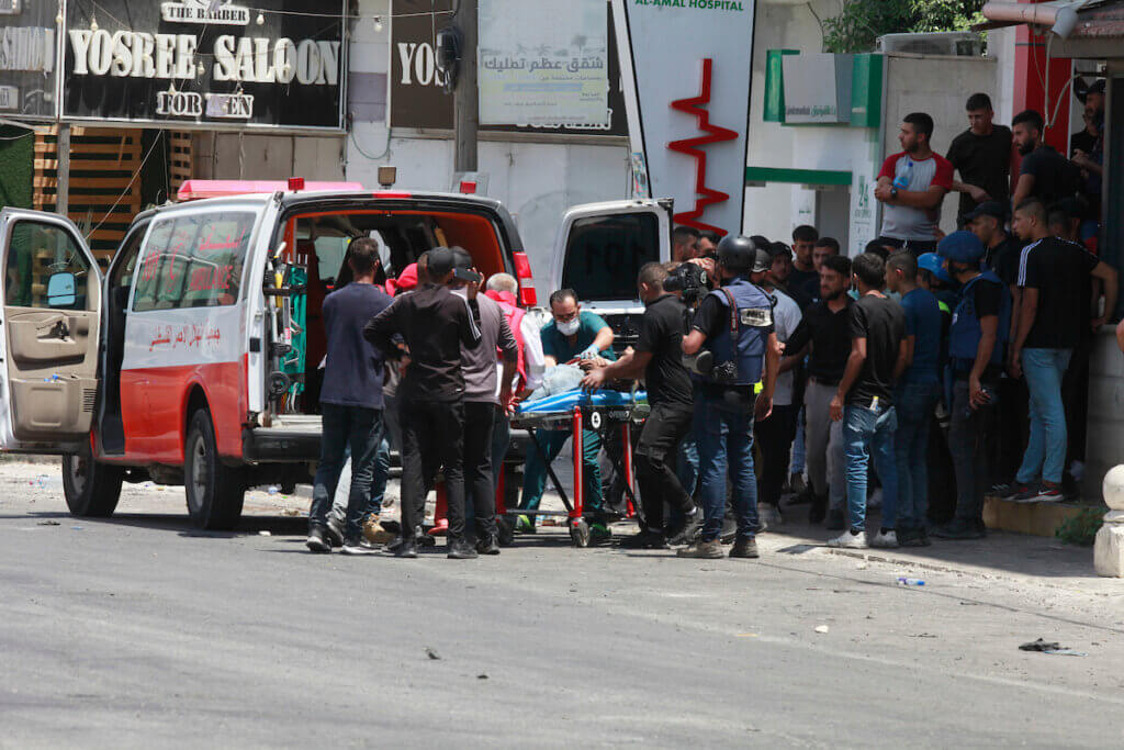 A photo of a crowd of people surrounding an ambulance that is evacuating injured Palestinians during an invasion of Jenin refugee camp.