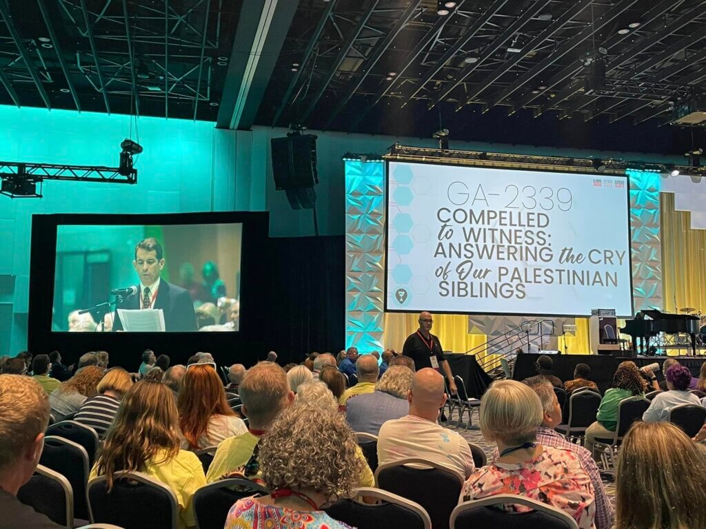Peter Makari, on the screen to the left, speaks in support of the resolution "Compelled to Witness: Answering the Cry of Our Palestinian Siblings" at the Christian Church (Disciples of Christ) biennial General Assembly in Louisville, Kentucky, July 29, 2023. (Photo: Social Media/Christian Church in Ohio, Disciples of Christ)