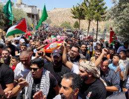 Funeral procession of Qusai Ma'tan, 19, in the village of Burqa, August 5, 2023. Mourners carry the body of Ma'tan on their shoulders. Ma'tan's body is draped with the Palestinian flag and a wreath of flowers lies on his chest.