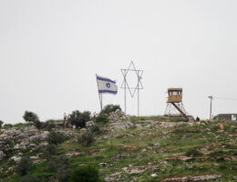 An Israeli flag, a Star of David sculpture, and a military watchtower stand atop a hill belonging to the lands of Beita, south of Nablus, as part of the Evyatar settlement.