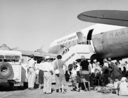A black-and-white photo of Iraqi Jews queuing to board an airplane to take them to Israel. The airline is operated by Near East Air Transport, an Israeli company.
