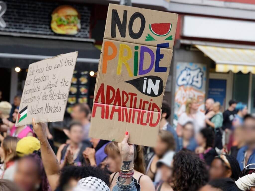 Protest organized by Internationalist Queer Pride for Liberation, Berlin, July 22, 2023. A protestor holds up a sign that reads "No Pride in Apartheid."