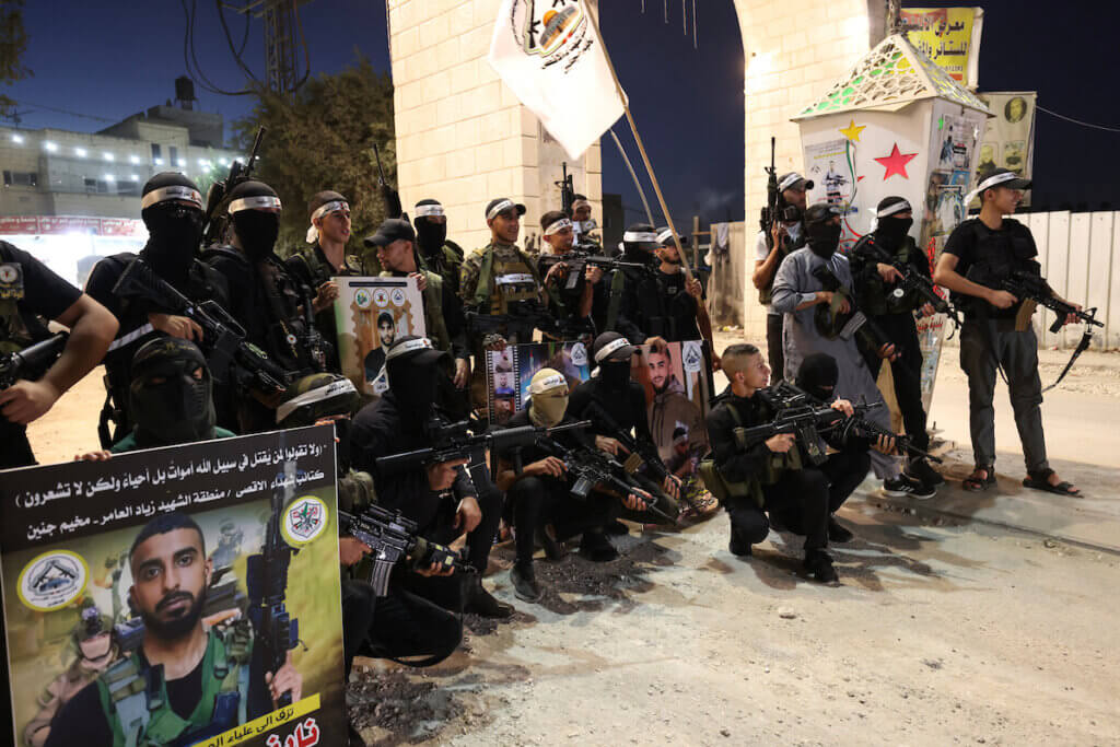 Palestinian resistance fighters gather during a memorial for their martyrs in Jenin refugee camp, September 16, 2023. The fighters are clad in black attire and sporting rifles and posing for a photo under an arch at the entrance of the camp.