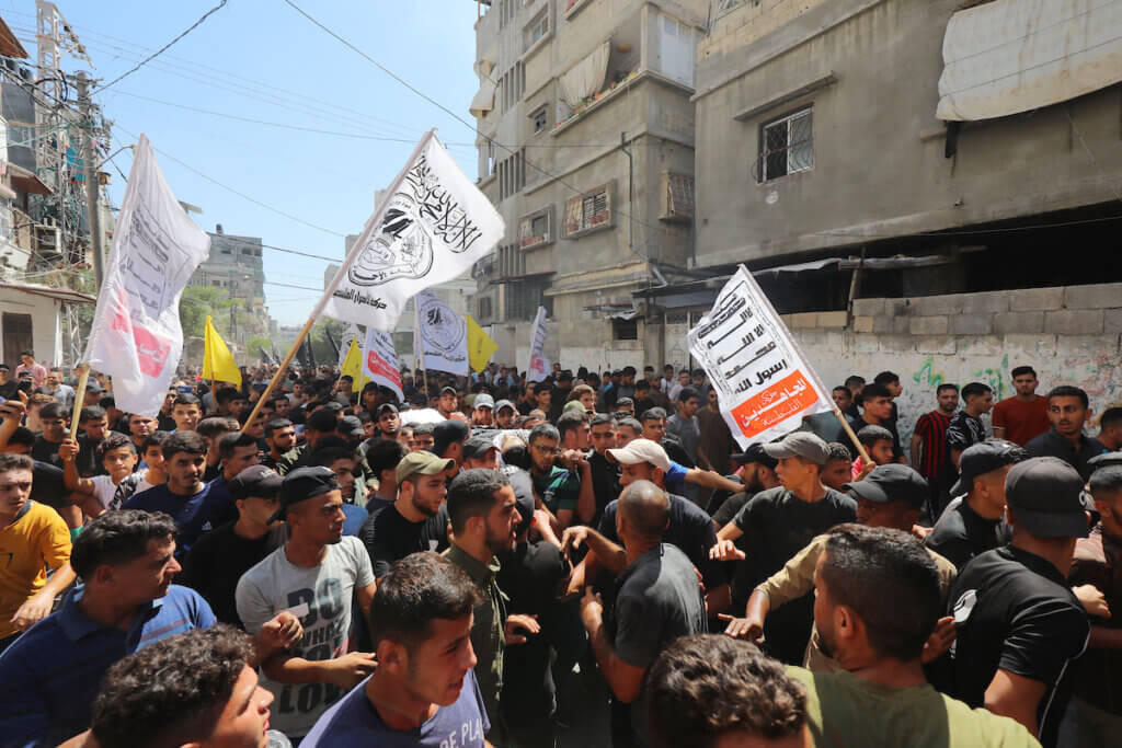 Mourners carry the body of Palestinian Majdi Ghabayen, who succumbed to wounds sustained in an explosion during a rally near the border fence with Israel on September 13, 2023. The photo is a snapshot of Ghabayen's funeral in Beit Lahia in the northern Gaza Strip on September 25, 2023, in which throngs of mourners carry his body and wave flags and banners.
