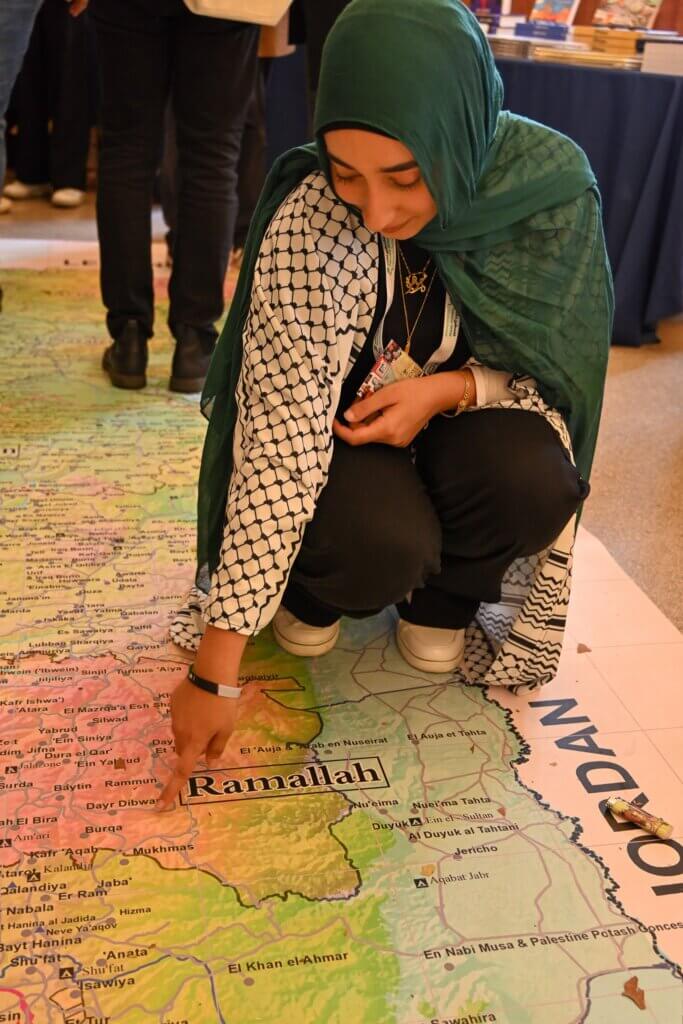 A visitor to the Palestine Writes Literature Festival points to a location on a map of Palestine, September 23, 2023. (Photo: Joe Piette courtesy of Palestine Writes)