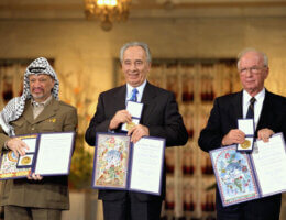 PLO Chairman Yasser Arafat (left), Israeli Foreign Minister Shimon Peres (center), and Israeli Prime Minister Yitzhak Rabin (right) each holding up the Nobel Peace Prize in 1994.